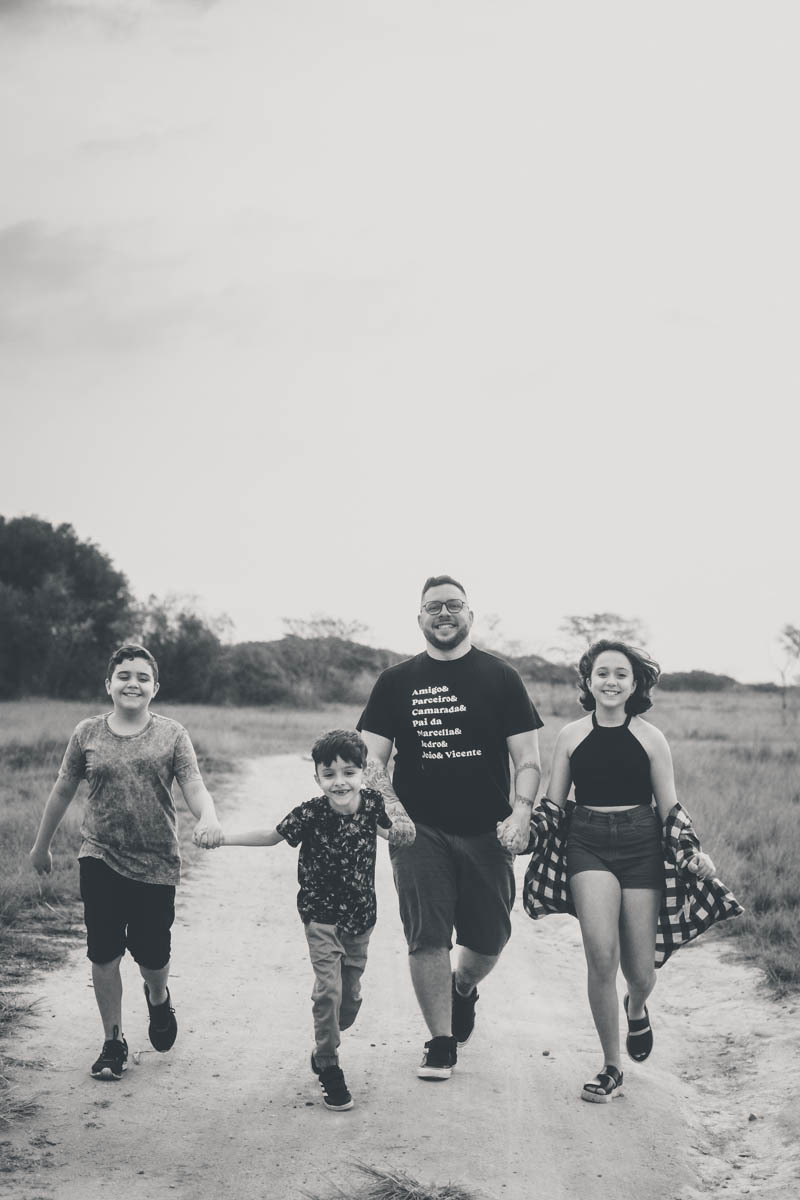 Pai sendo fotografado caminhando com seus filhos em ensaio fotografico na ilha do governador