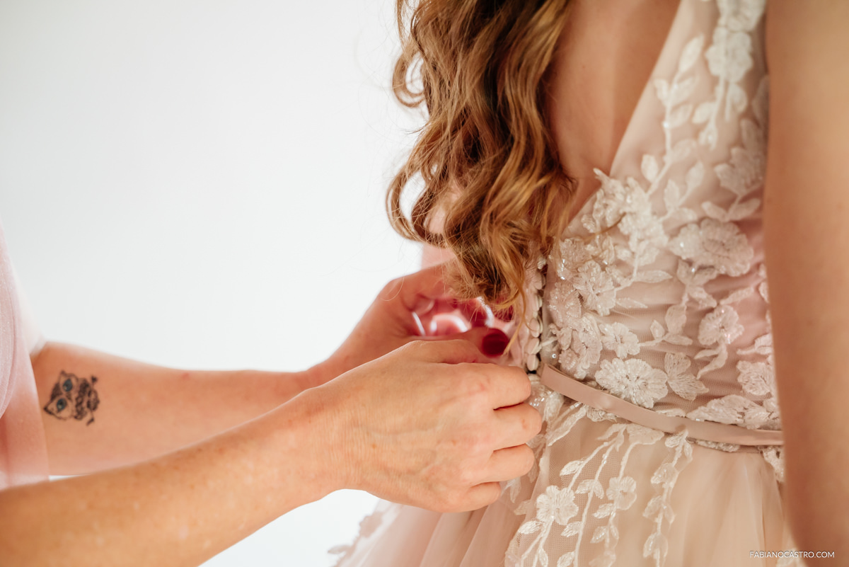 a mamãe da Luiza ajudando com o vestido de noiva