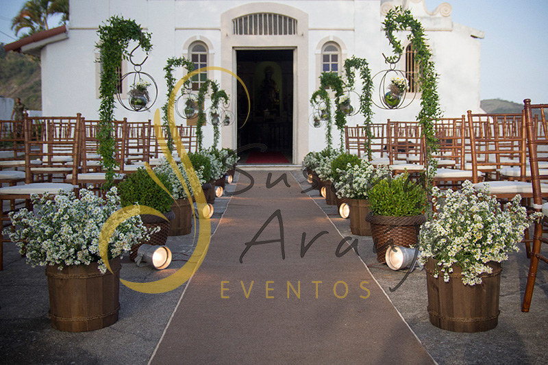 Casamento Zéfiro Niterói, cerimônia na Fortaleza de Santa Cruz, Capela de Santa Bárbara com flores brancas, suporte de ferro com flores, buchinhos.