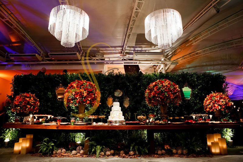 Casamento Zéfiro Niterói, mesa de doces e bolo. com flores vermelhas e laranja, muro inglës e lustres.