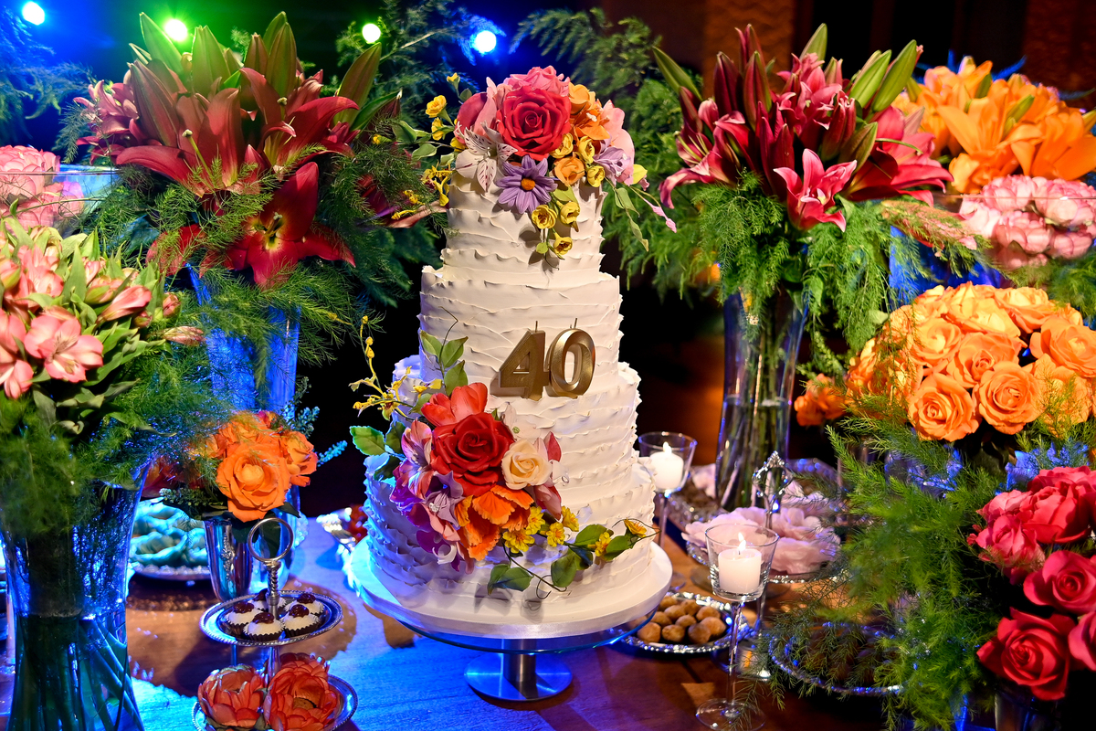 Aniversário de 40 anos - Rio Cricket - Mesa de bolo e doces com flores em tons de laranja, rosa e marsala.