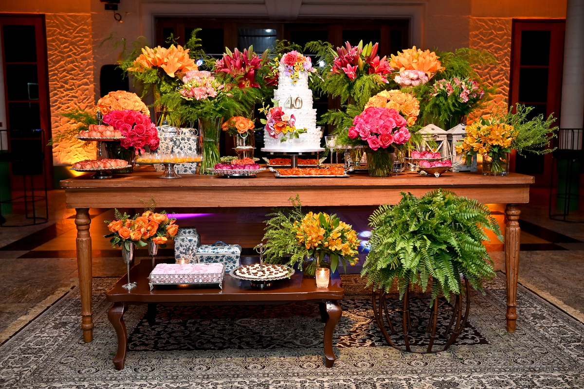 Aniversário de 40 anos - Rio Cricket - Mesa de bolo e doces com flores em tons de laranja, rosa e marsala.
