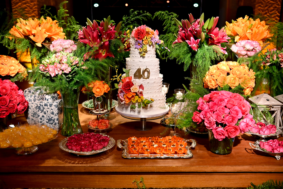 Aniversário de 40 anos - Rio Cricket - Mesa de bolo e doces com flores em tons de laranja, rosa e marsala.