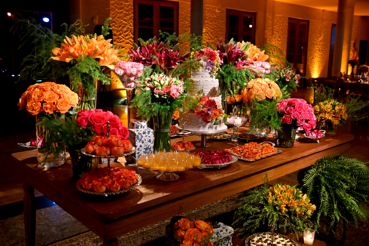 Aniversário de 40 anos - Rio Cricket - Mesas de convidados com flores em tons de laranja, rosa e marsala, móveis em madeira.
