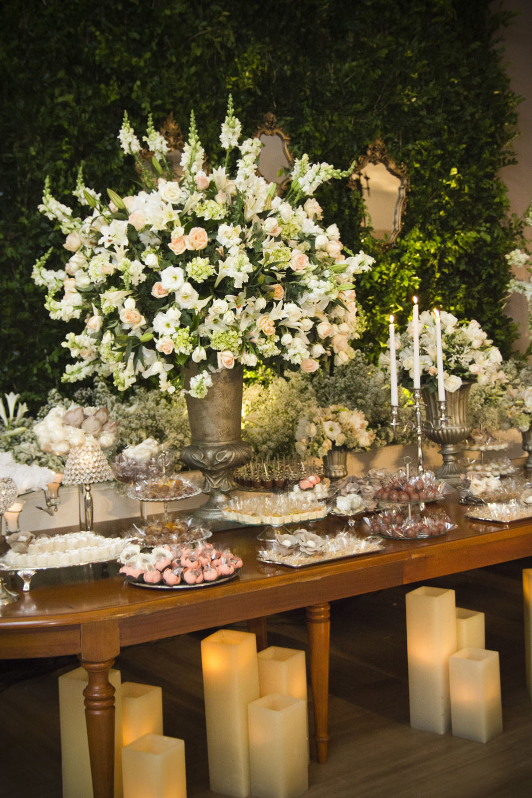 Casamento Rio Cricket Niterói, mesa de doces e bolo com flores e arranjos de flores brancas, e mobiliário de madeira.  Velas, 