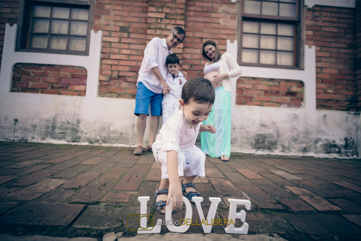 Menino levado mexendo na palavra love durante a sessão fotográfica