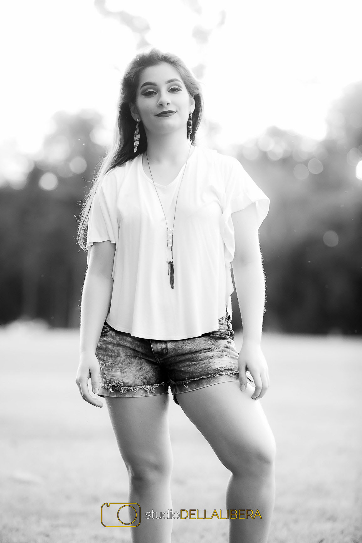 Alanis modelando de camisa branca e shorts jeans com a foto em PB no gramado central da Esalq