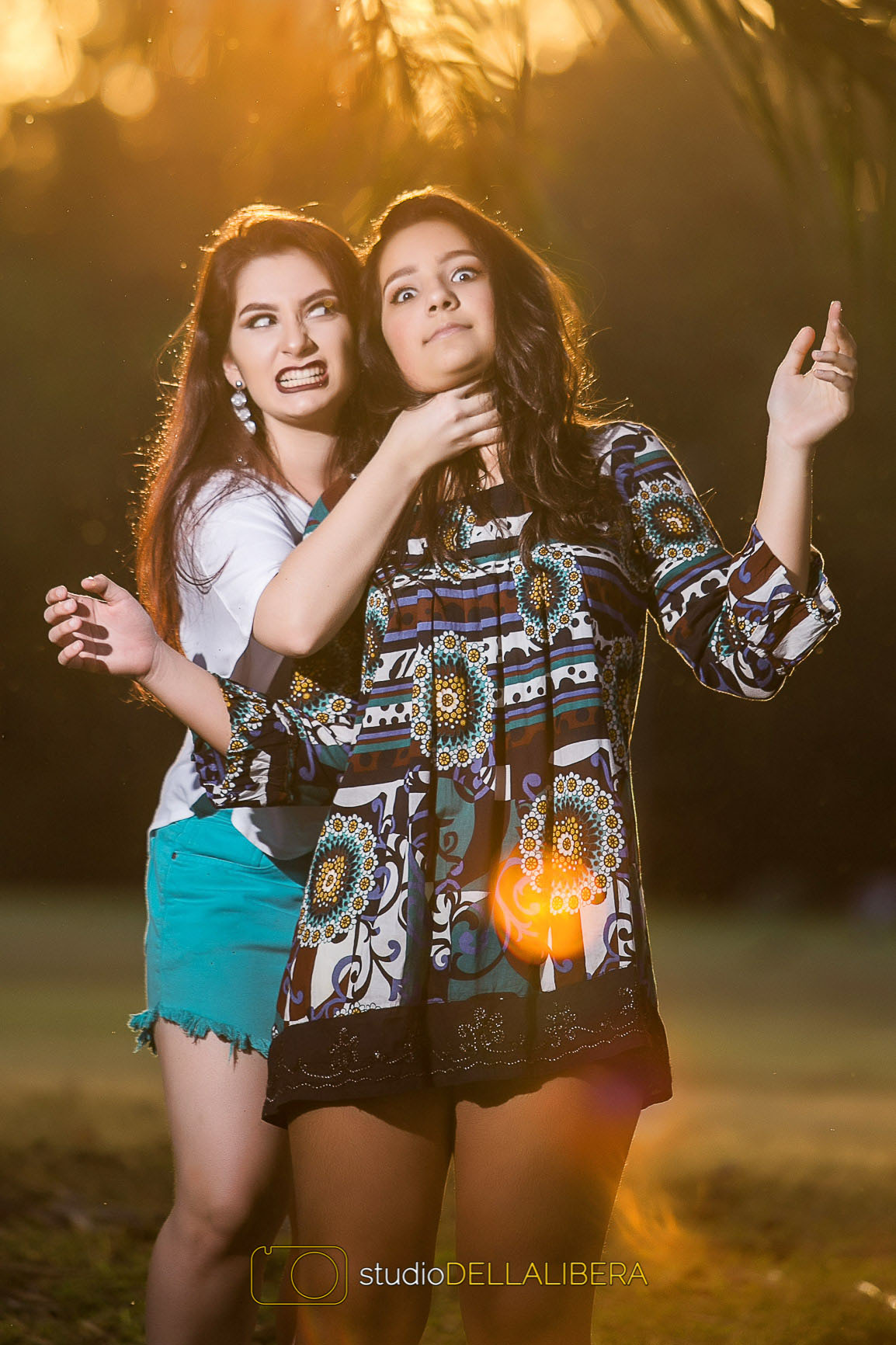 Alanis enforcando Laura na divertida sessão fotográfica feita em um parque em meio a muito verde com o fotógrafo e pai Wilson do studio Dellalibera