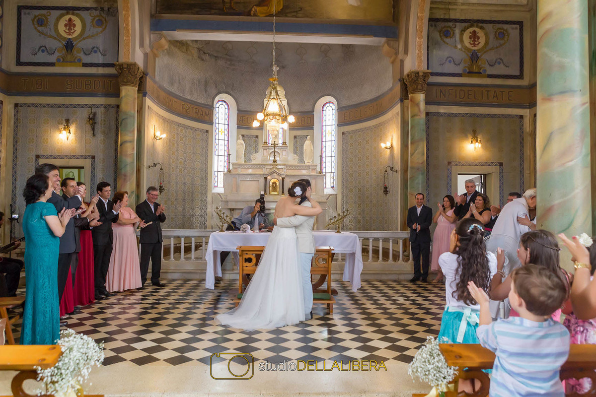 Beijo dos noivos após a troca de alianças no altar da igreja Monte Alegra em com aplausos dos padrinhos