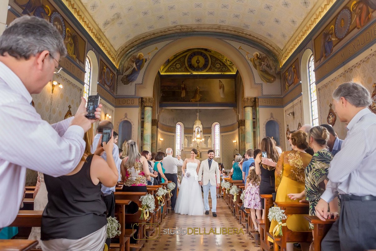 Noivos no corredor da igreja Monte Alegre em Piracicaba, decorado com mosquitinhos recebendo aplausos
