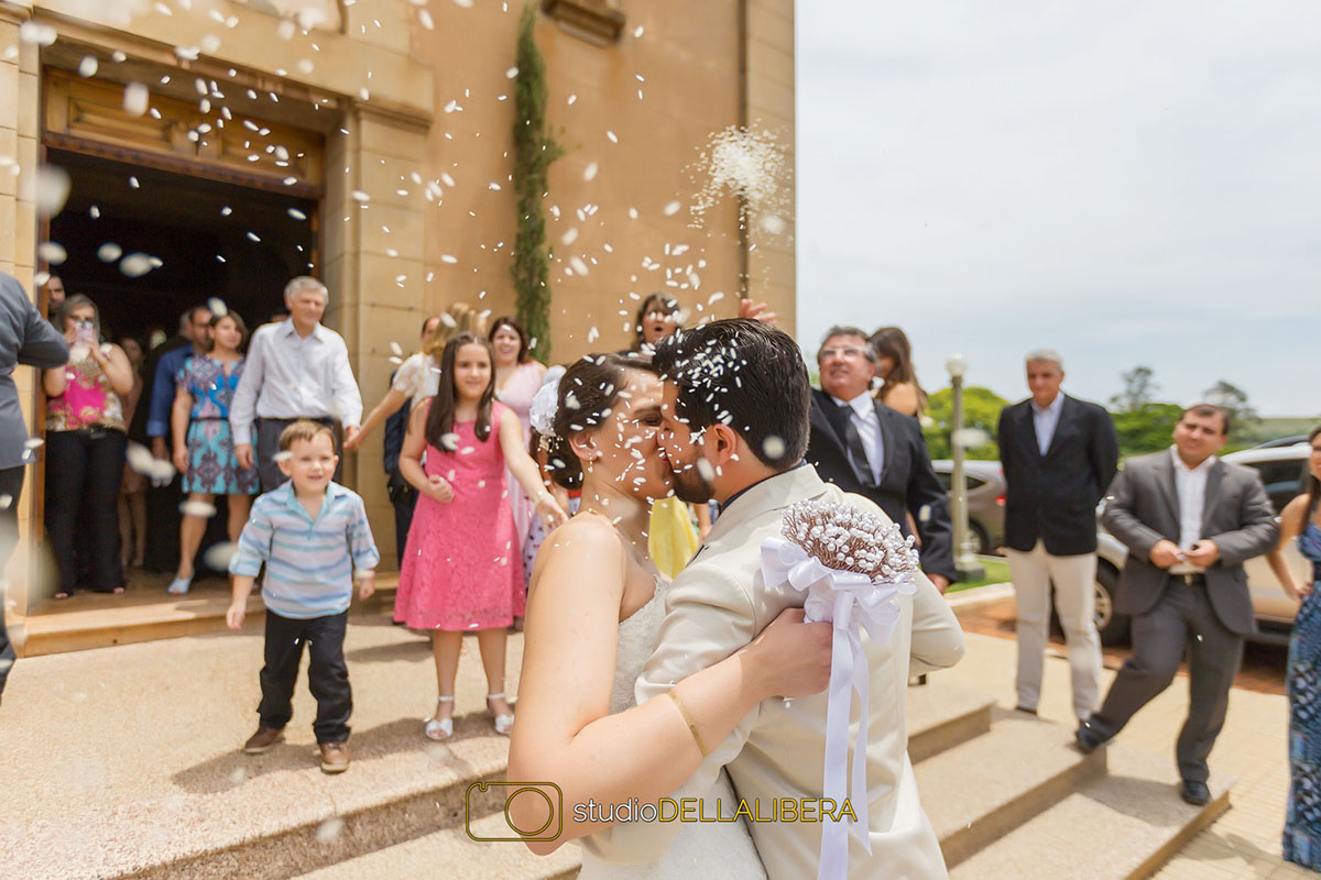 Beijo dos noivos recebendo chuva de arroz na saida da Igreja Monte Alegre em Piracicaba