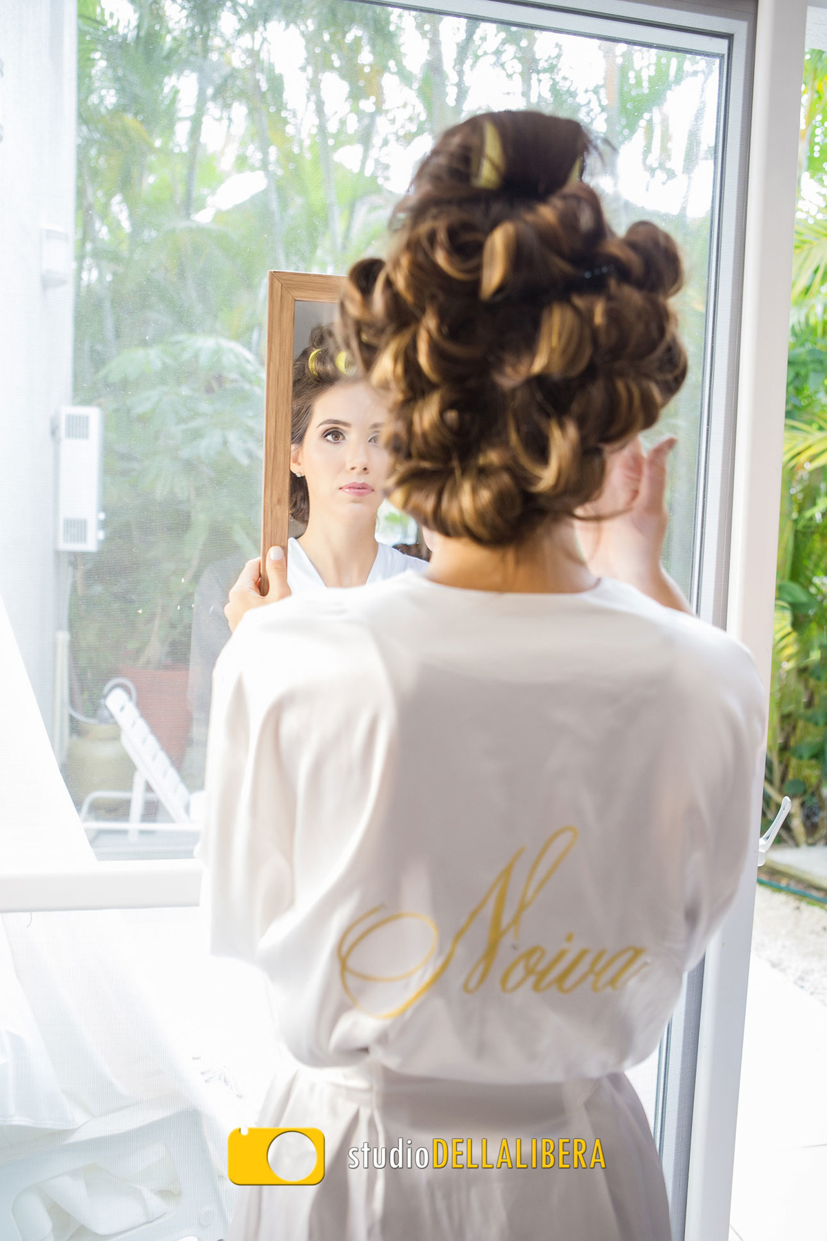 Noiva Gabriela conferindo a maquiagem no espelho na casa de Praia