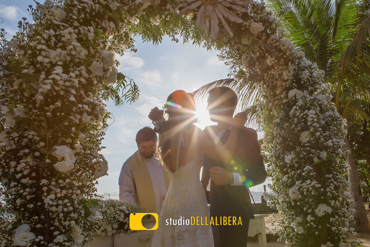 Noivos quase se beijando logo após a troca de alianças no casamento que foi realizado na Reserva Tambá, casamento realizado na praia de Maresias com o sol brilhando de fundo.