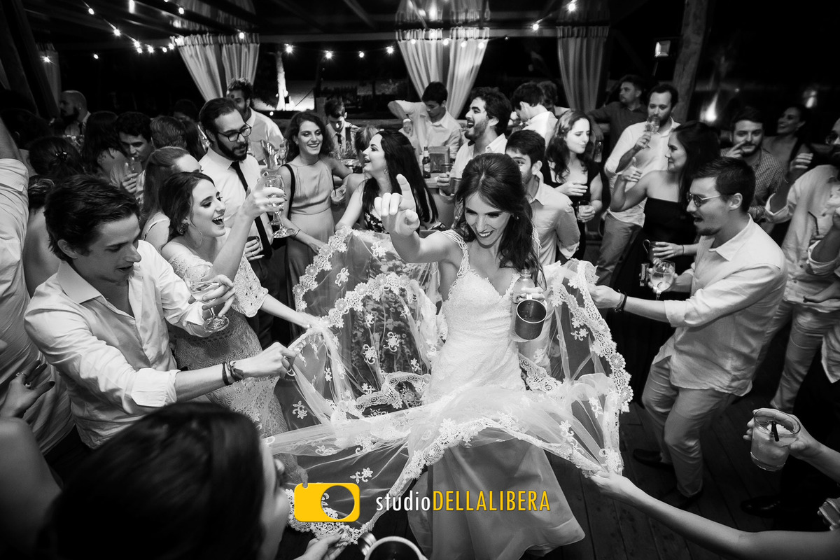 Noiva dançando com amigas segurando seu vestido durante a festa de casamento realizado na praia de Toque Toque pequeno na reserva Tambá