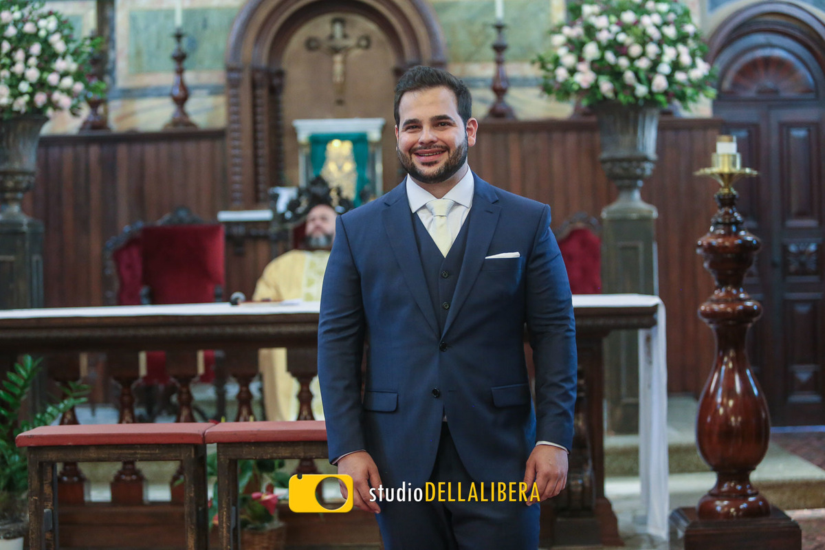 Noivo usando terno azul aguardando a noiva no altar de Igreja dos Frades, decorada com flores brancas pela floricultura Verde Total