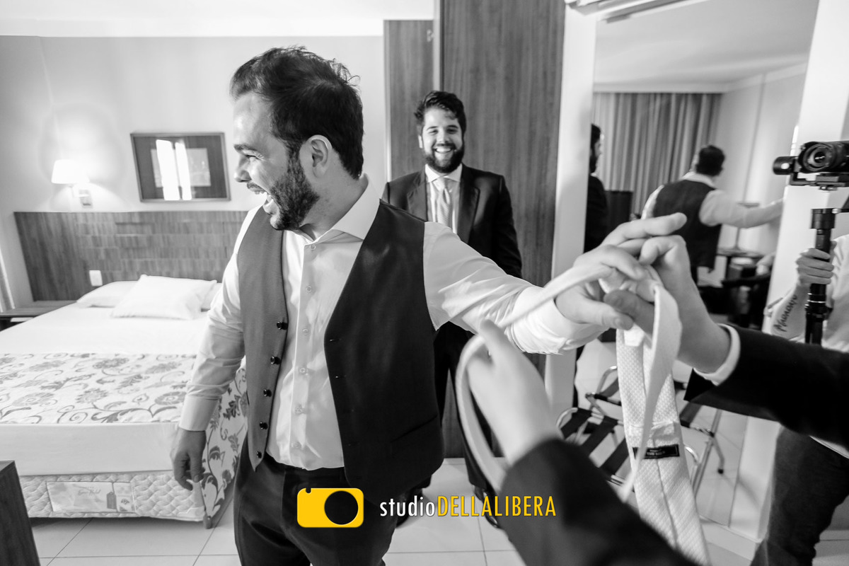 Noivo no making-fo com os amigos no quarto de hotel em Piracicaba SP, pegando a gravata da mão de um dos amigos prontos para o casamento