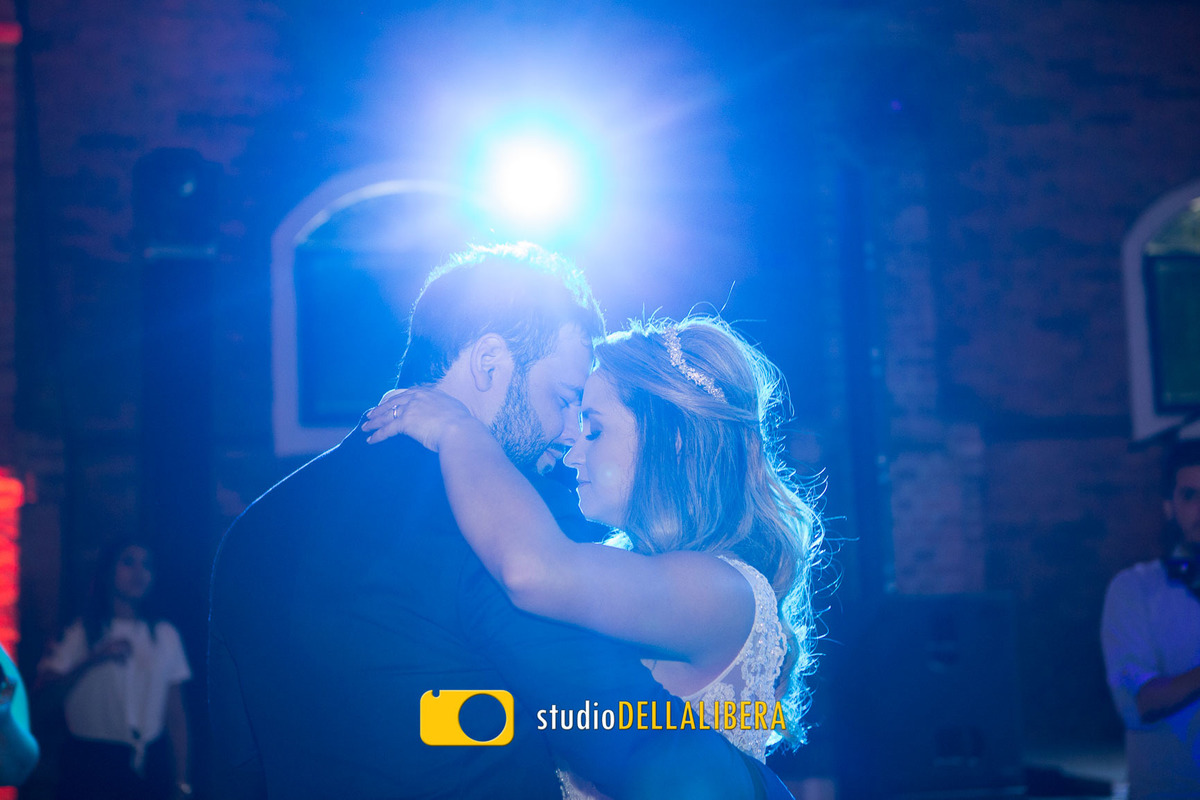 Casal de noivos dançando a valsa com a testa colada um no outro de olhos fechados com luz azul ao fundo no buffet Zara em Piracicaba foto sendo feita pelo fotografa de casamento  Emanuela