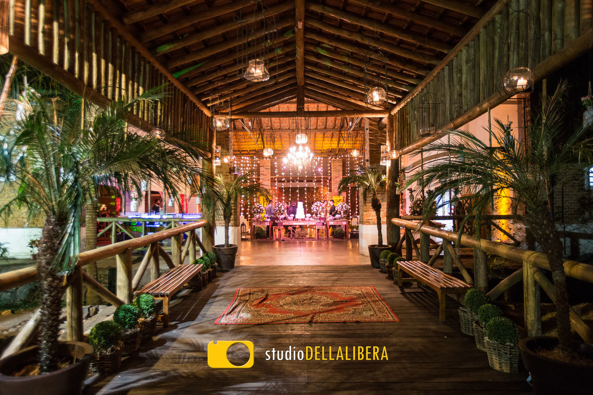 Recepção do espaço Zara em Piracicaba SP decorado pela Verde Total com palmeiras na lateral bancos rústicos ao fundo a mesa do bolo