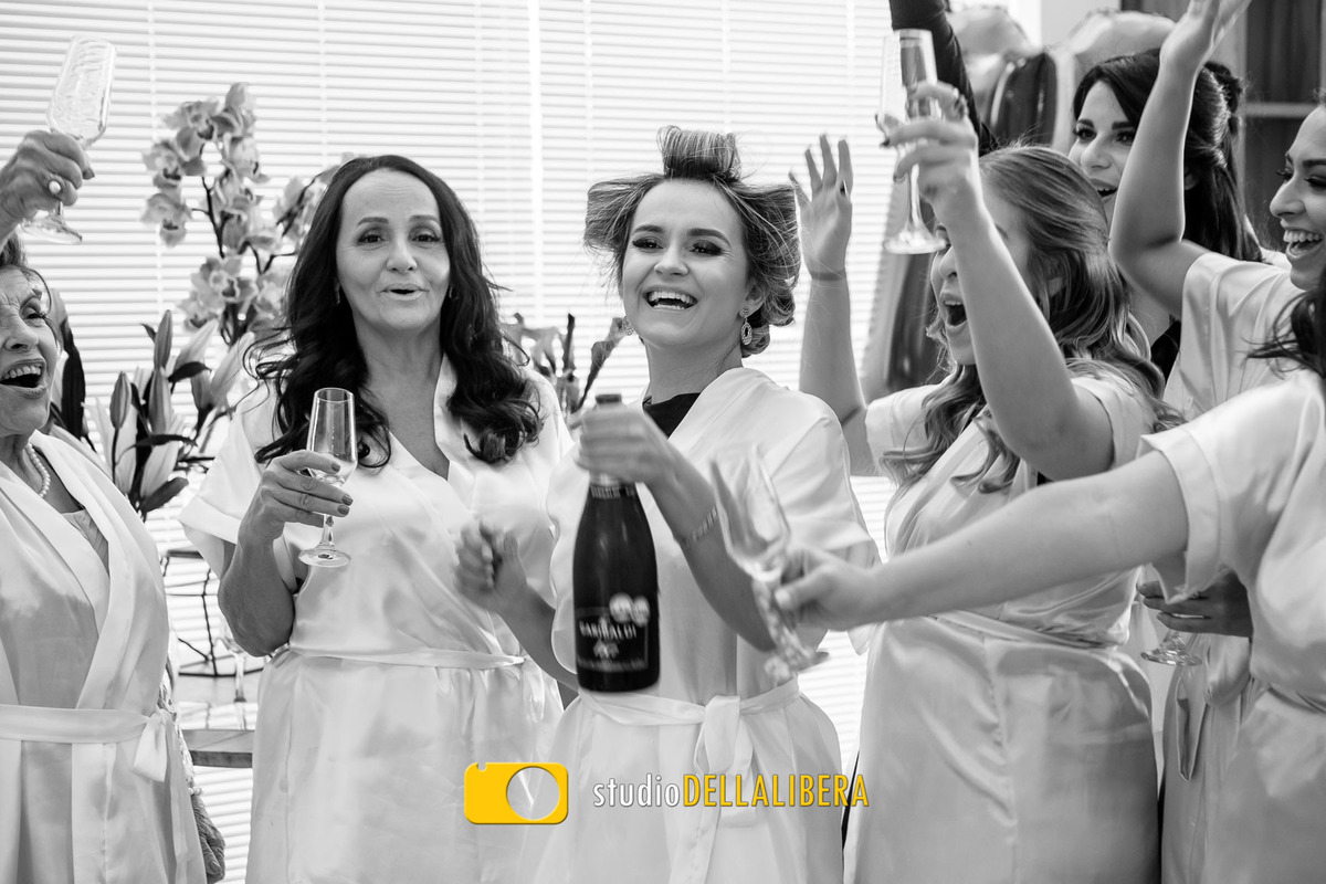 Noiva logo após abrir a garrafa com as madrinhas comemorando, com as taças pra cima no salão de beleza Alex Mendes em Piracicaba-SP