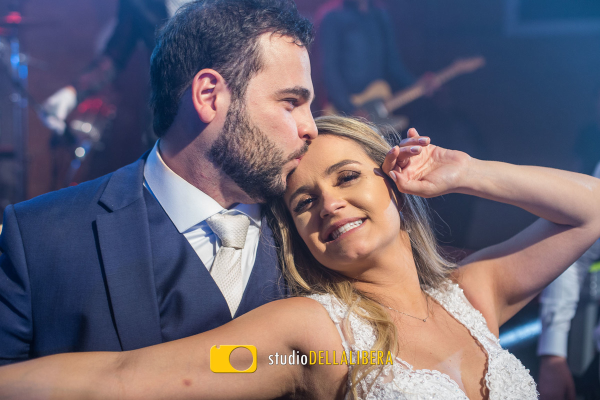 Foto espontânea registrada pelo fotografo de Casamento Wilso Della Libera Junior com os noivos dançando no salão o noivo dando um beijo na testa da noiva, os dois divertindo muito com a festa sendo animada pela banda Viva Noitr
