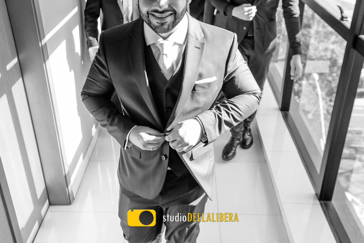 Noivo fechando o botão do terno no corredor do hotel com os padrinhos vindo atraz saindo para o casamento na Igreja dos Frades em Piracicaba SP