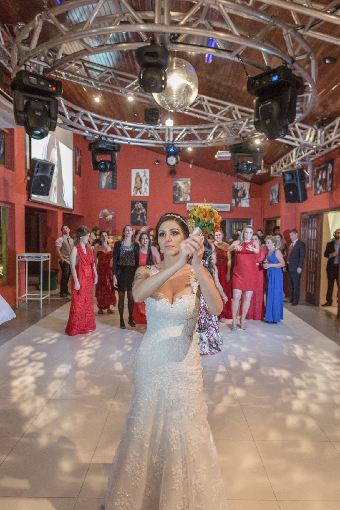 Noiva segurando o buque para jogar para as convidadas ao fundo