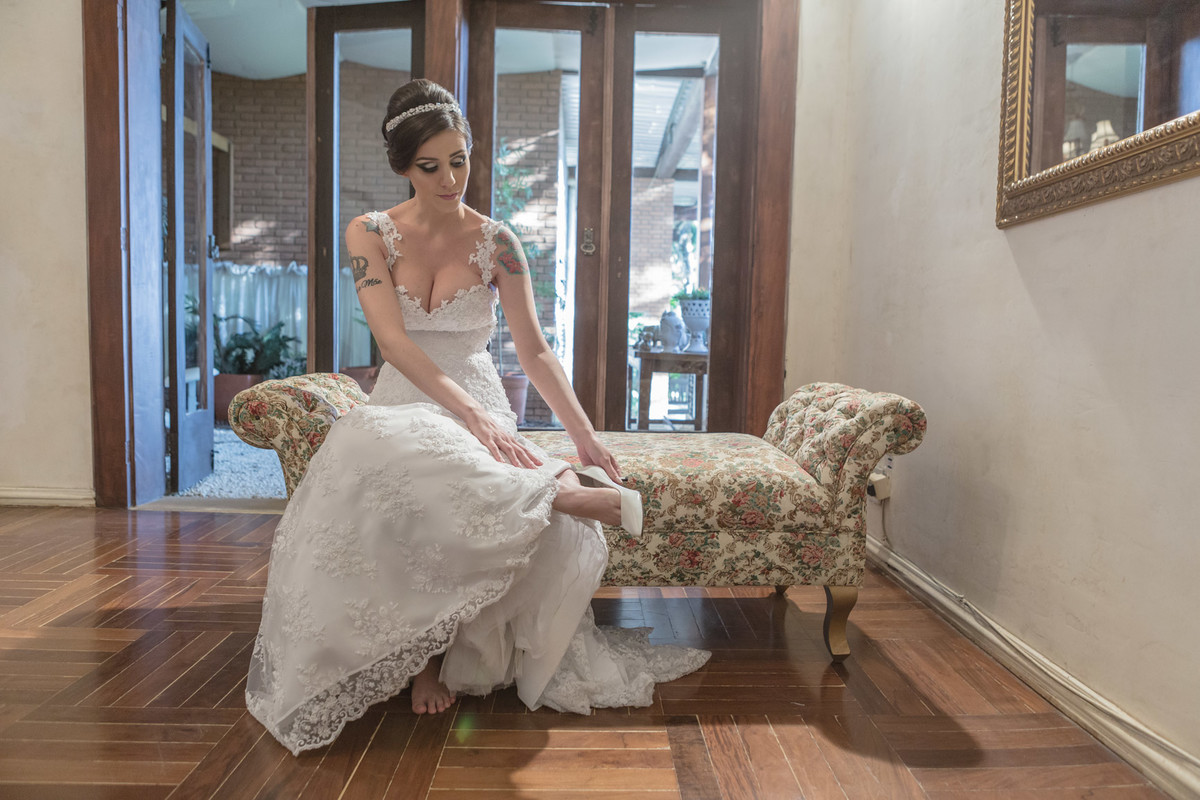 Noiva sentada colocando seu sapato momentos antes da cerimônia