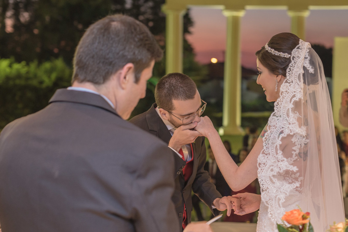 Noivo beijando a mão da noiva enquanto ela o olha