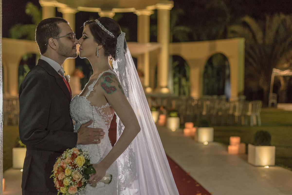 Noivos se beijando com noiva segurando o buque em suas mãos