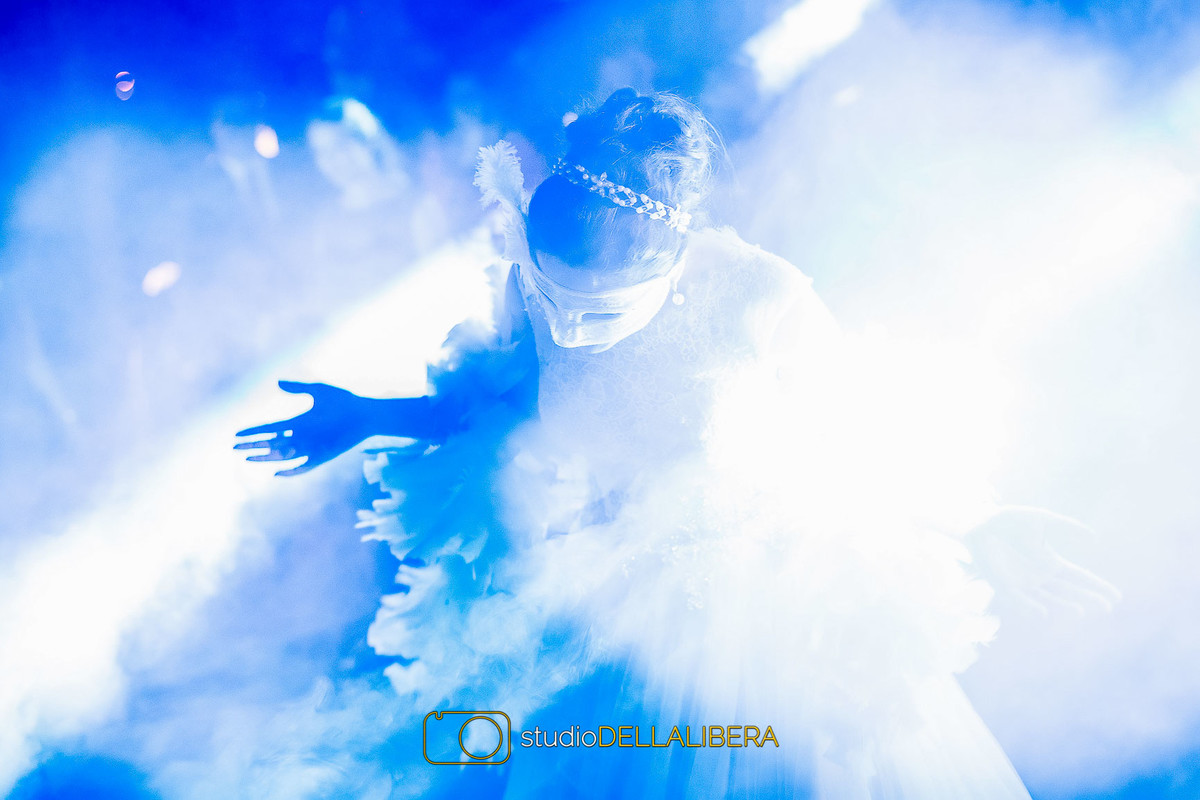Juliana dançando com mascara e sendo iluminada por luz azul