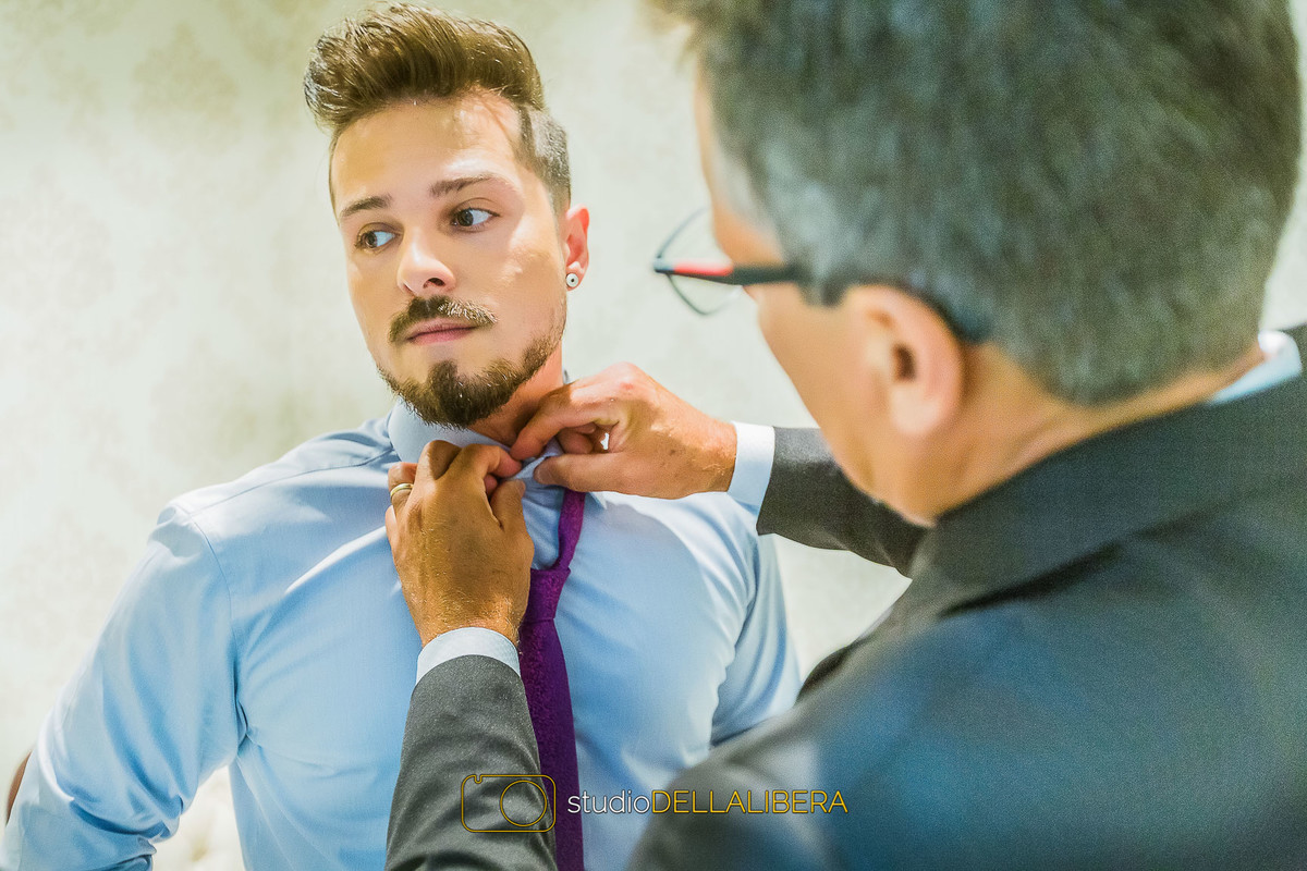 Pai do noivo arrumando a camisa azul do filho momentos antes do casamento acontecer