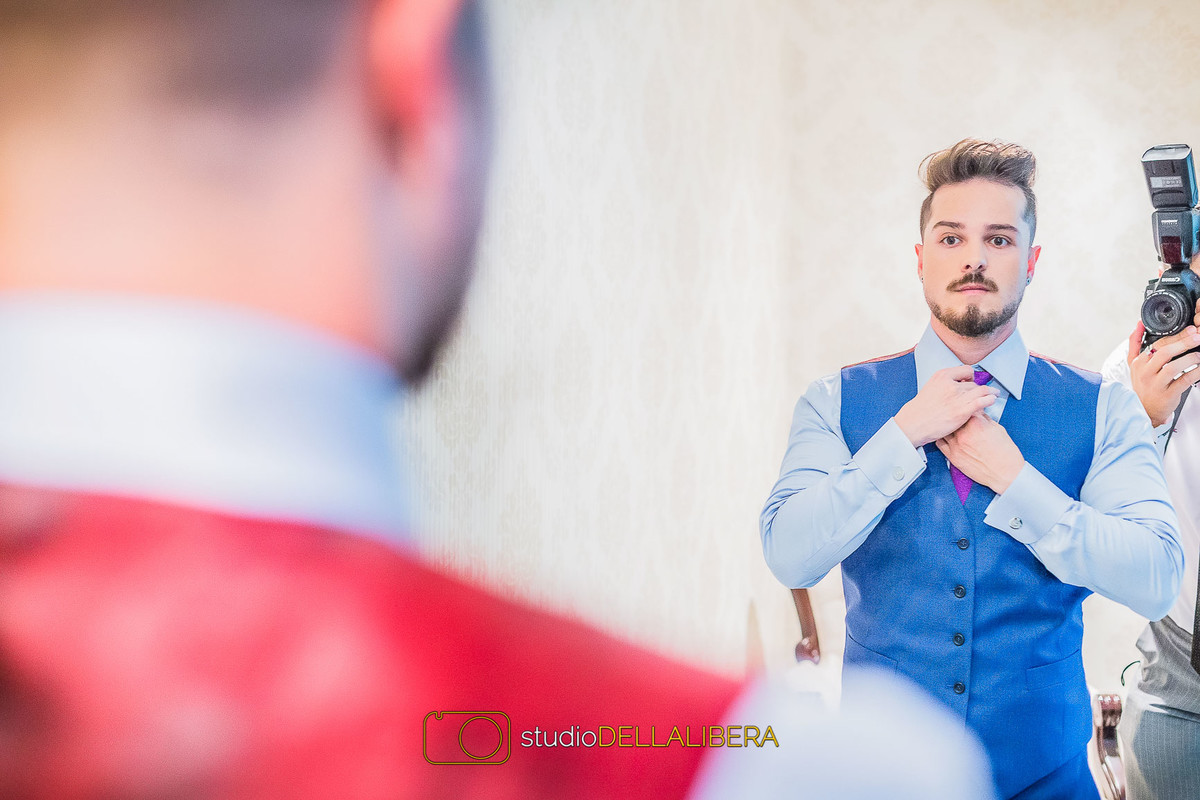 Noivo arrumando a gravata roxa em frente ao espelho