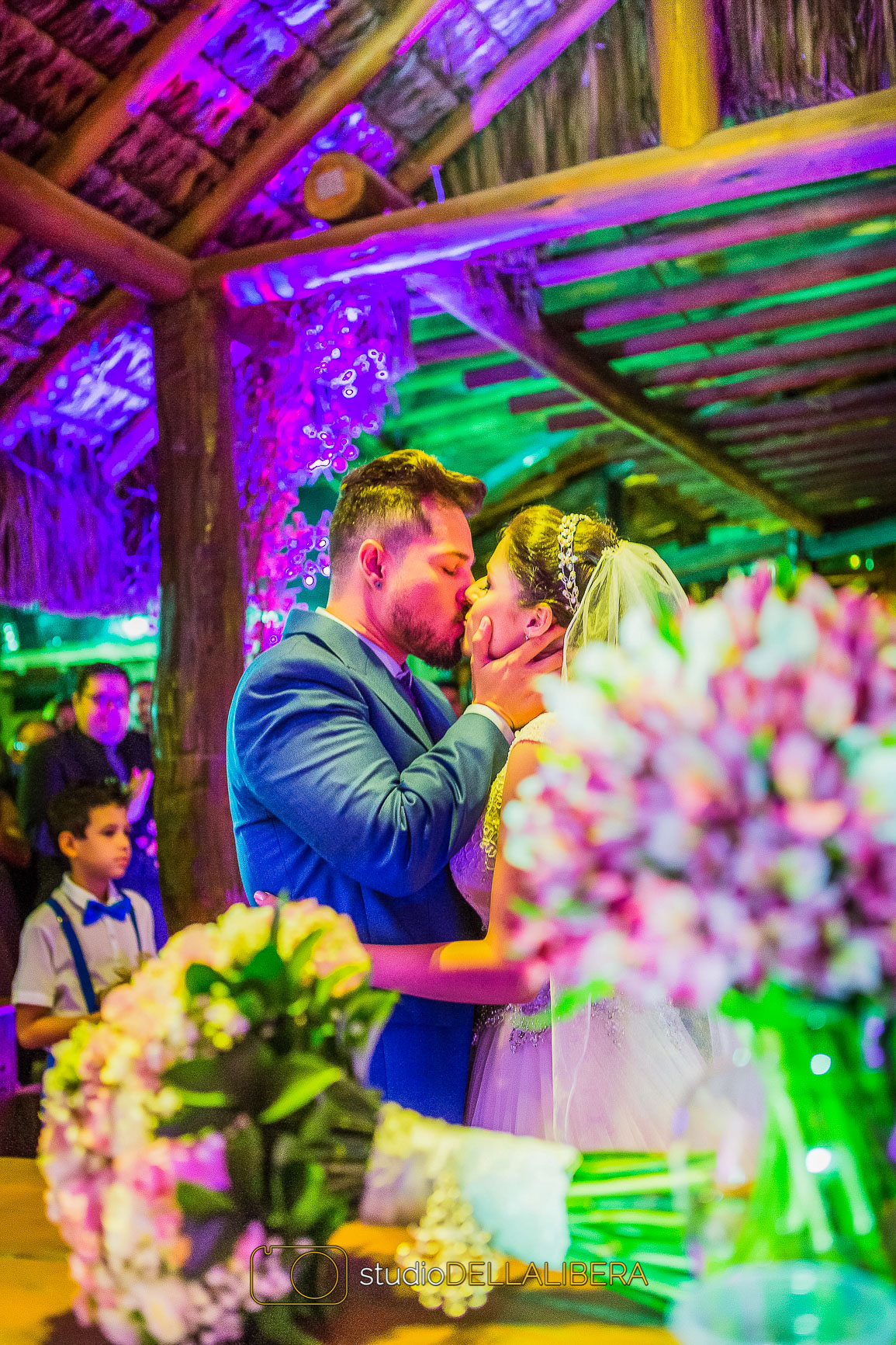 Buque de flor da noiva e decoração com noivos se beijando ao fundo