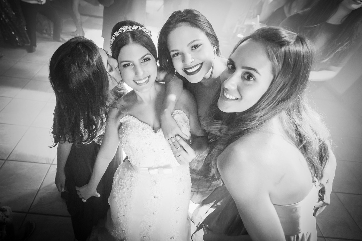 Noiva com suas amigas recebendo um beijo na bochecha de uma delas