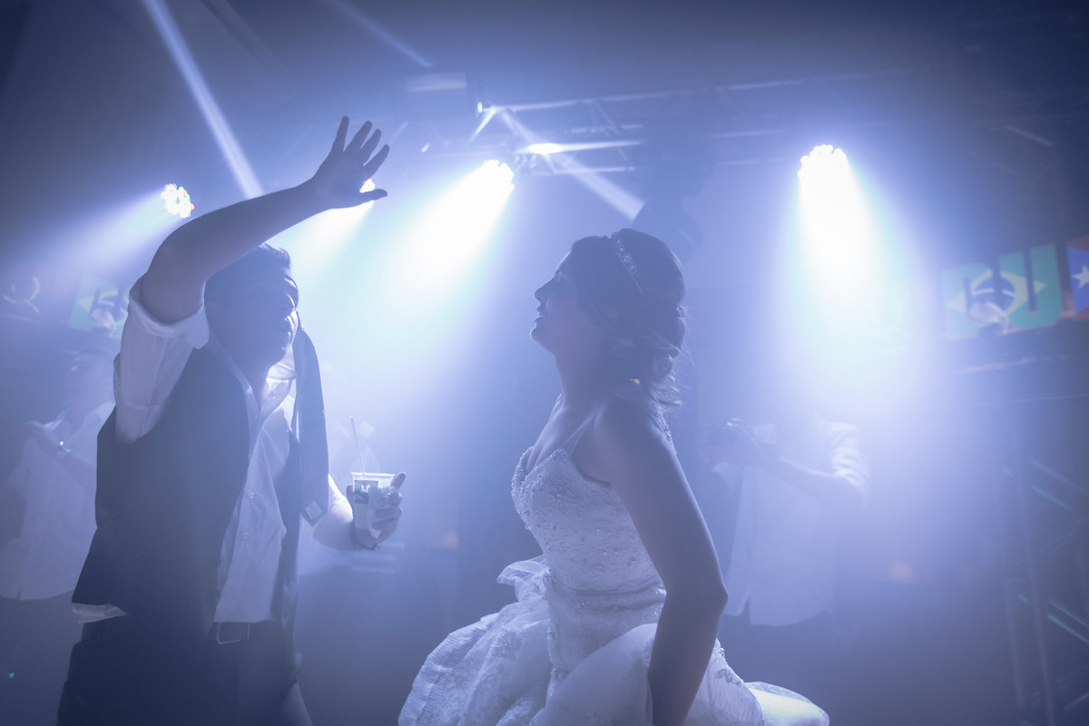 Noiva dançando de olhos fechados enquanto o noivo se diverte com gravata na cabeça