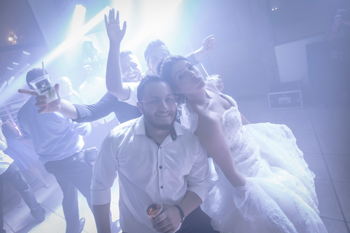Noivos posando para foto com amigos na pista de dança