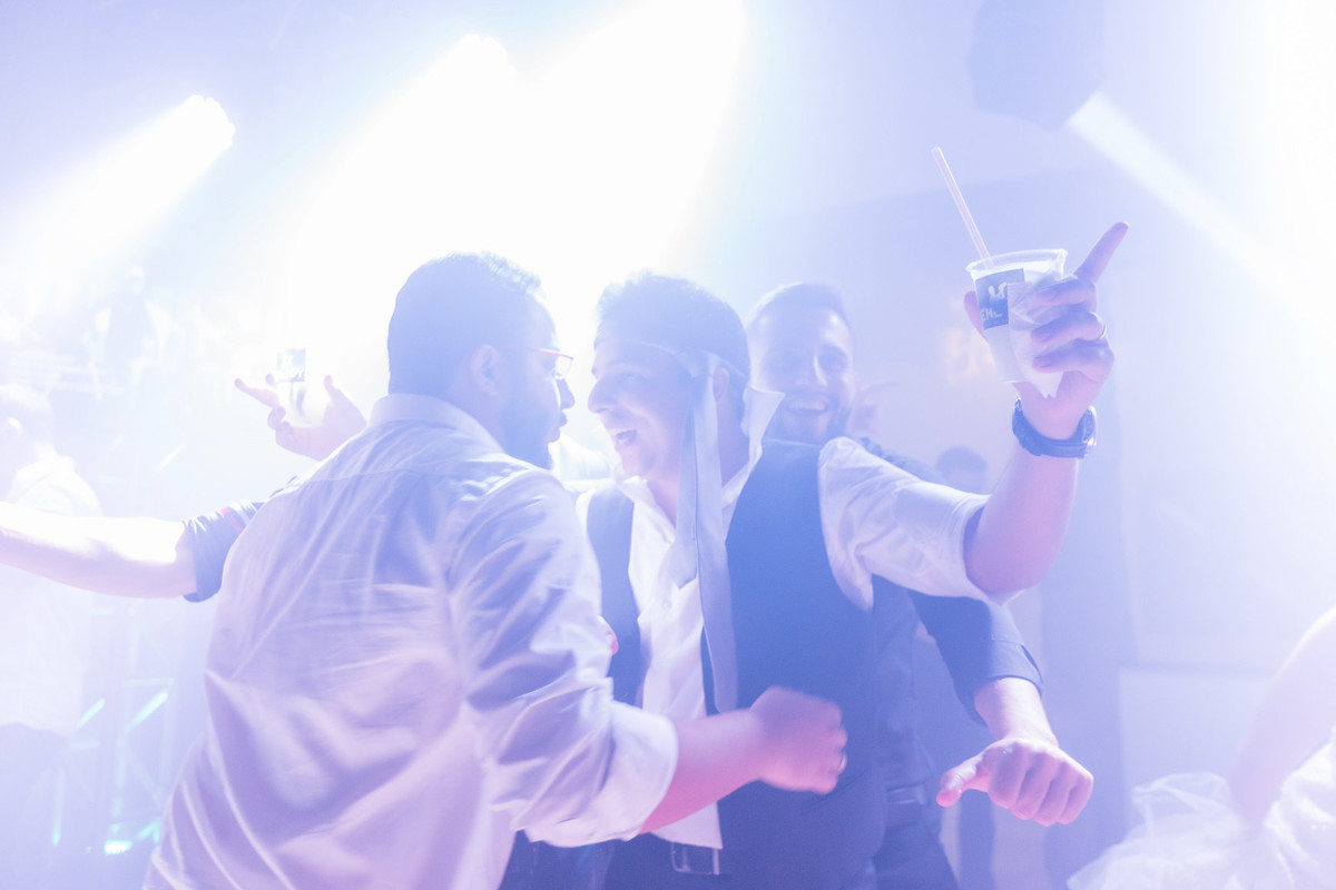 Noivo na pista de dança segurando drinks enquanto conversa com amigos