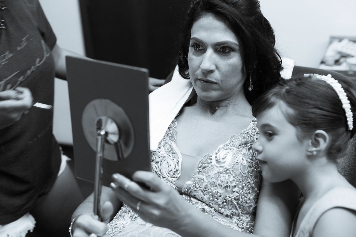 Mãe da noiva se olhando no espelho sentada com criança espiando