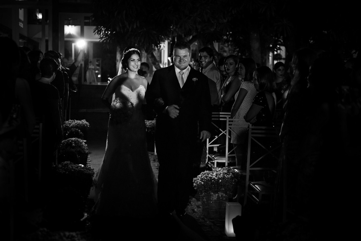 Noiva entrando no altar com seu pai ao lado e convidados a olhando