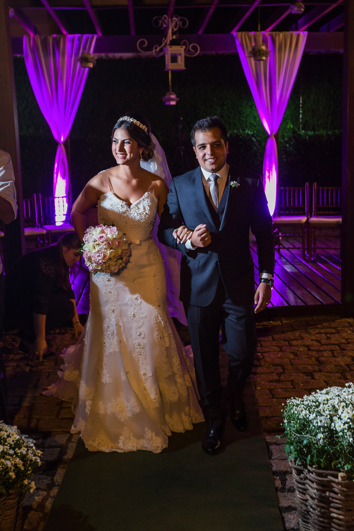 Noivos de mãos dadas saindo do altar e noiva segurando seu buque