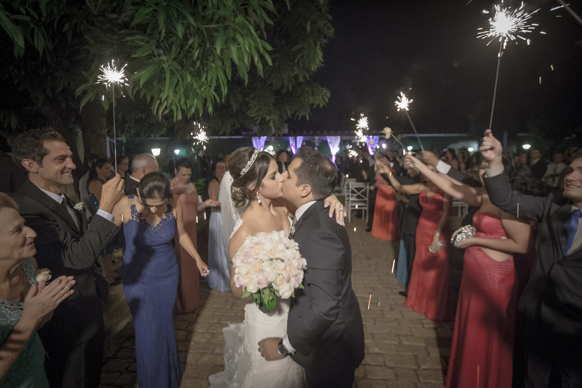 Noiva segurando o buque de flores enquanto noivo a beija