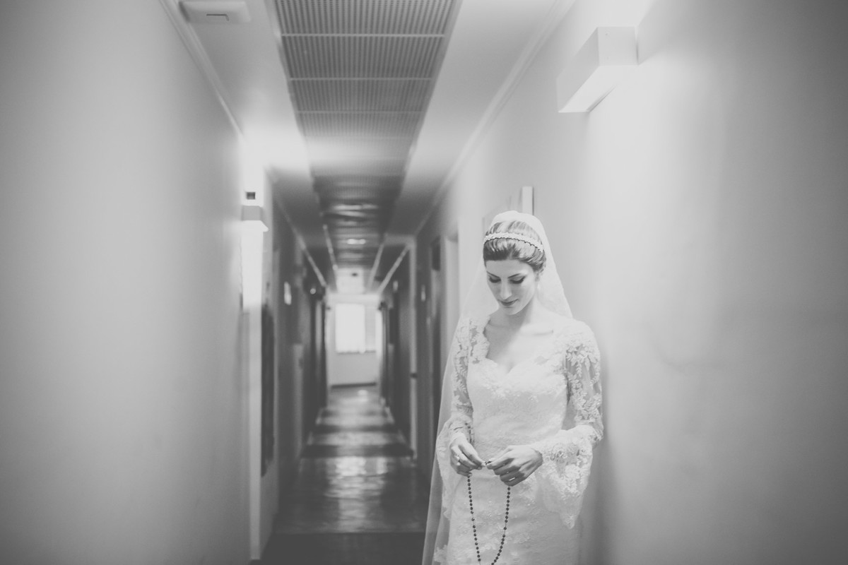 Noiva pronta para casar com vestido segurando um terço fazendo as ultimas preçes encostada na parede