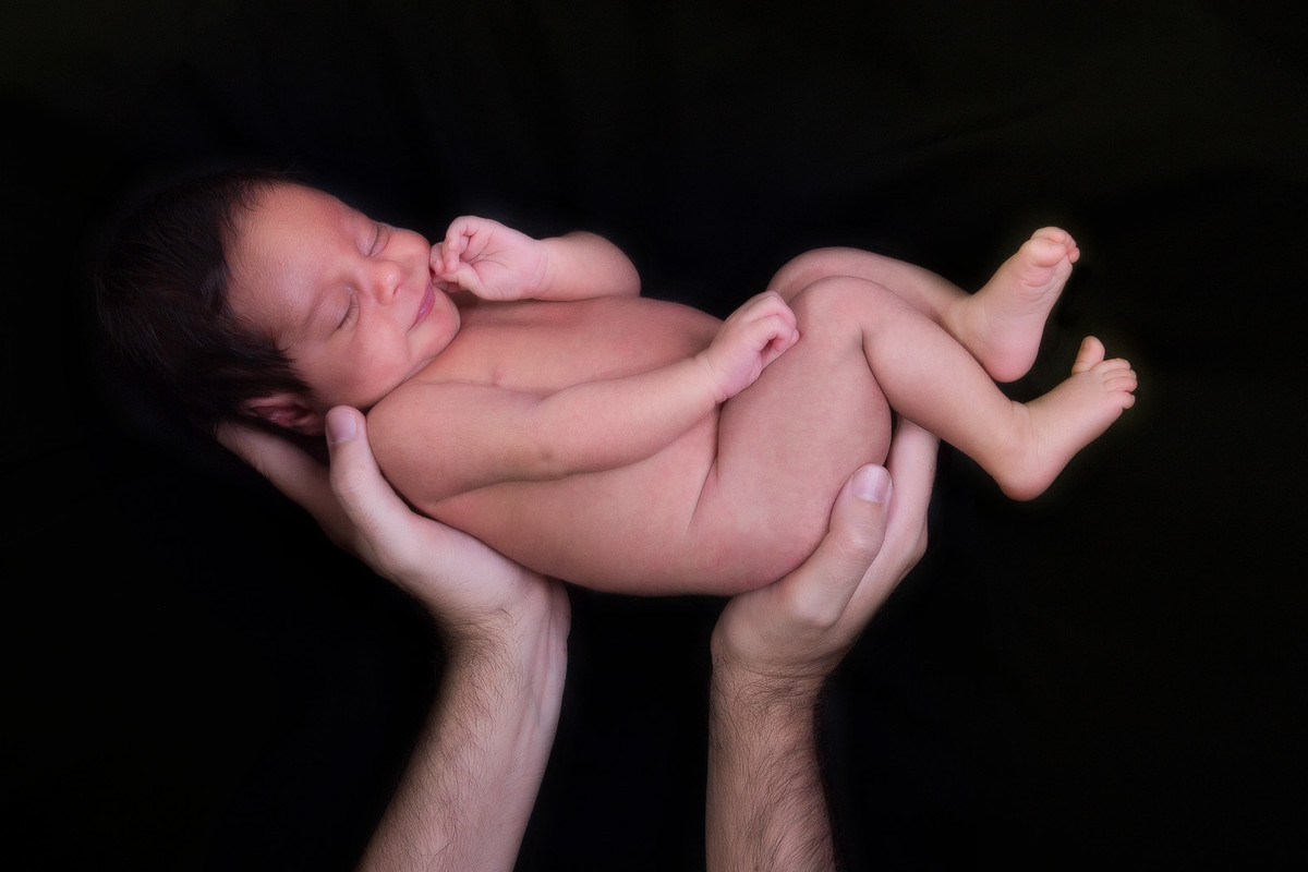 Pai segurando o bebê em sessão fotográfica newborn Piracicaba