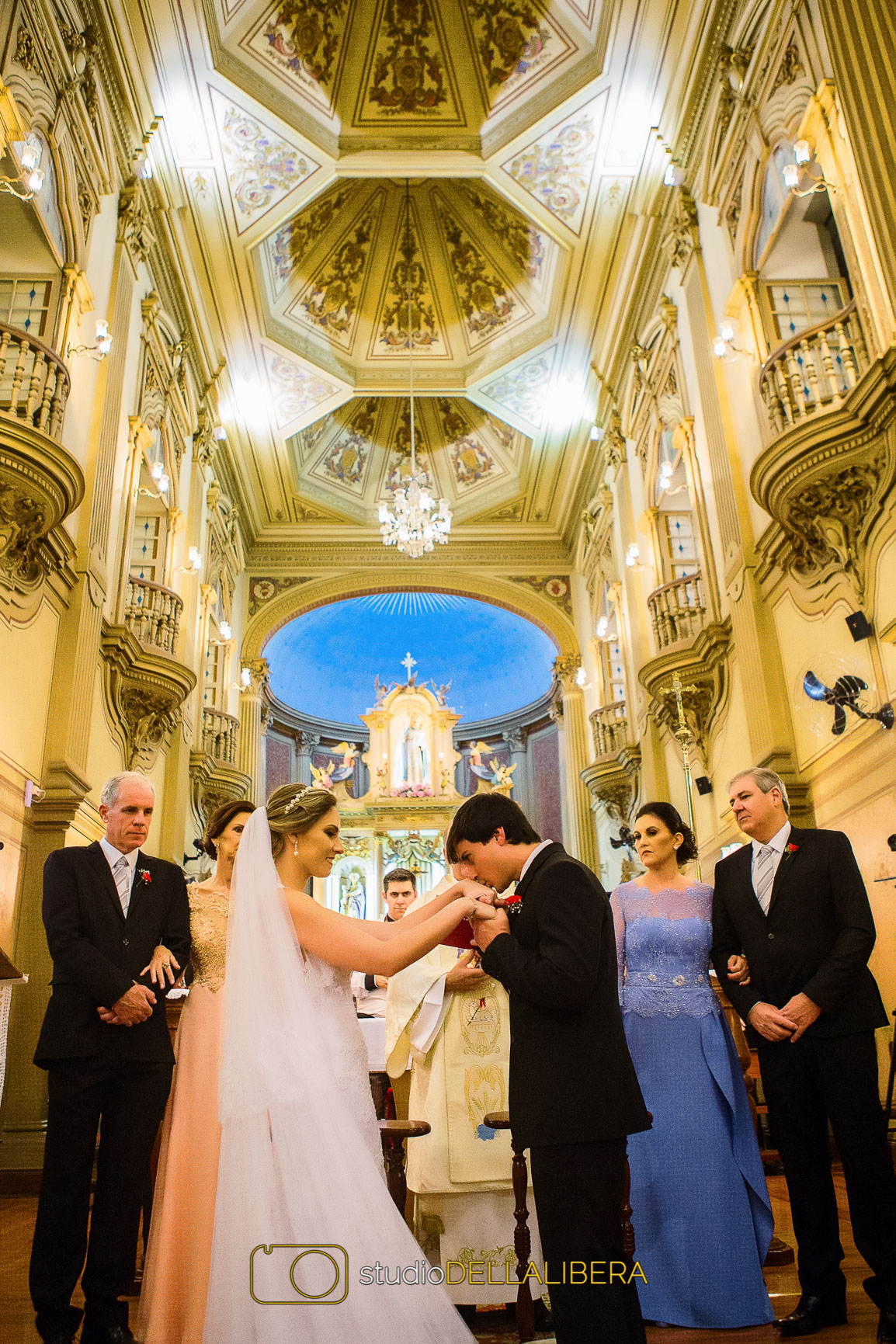Noivo Beijando as mãos da noiva na Igreja Nossa Senhora do Patrocínio, com os páis ao fundo