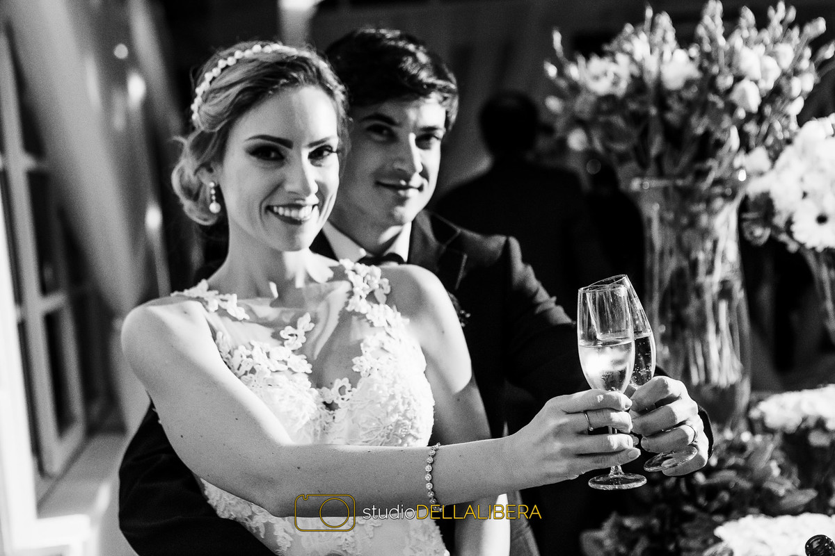 Noivos brindando  com campagnhe na mesa de bolo