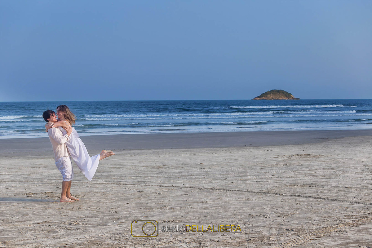 noivo levantando a noiva na praia e beijando com um cenário espetacular, as fotos do casamento promete