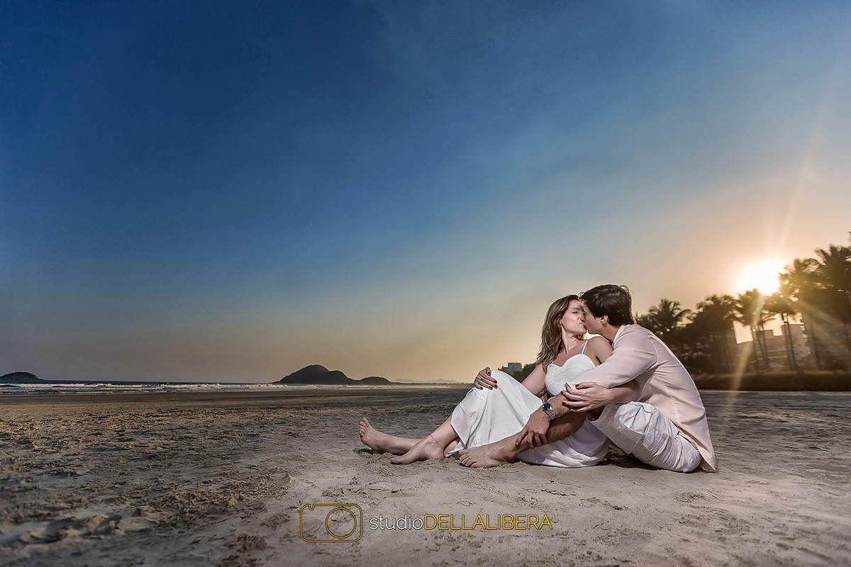 Com céu azul o sol se pondo e mais um beijo do casal na sessão pré wedding em Bertioga