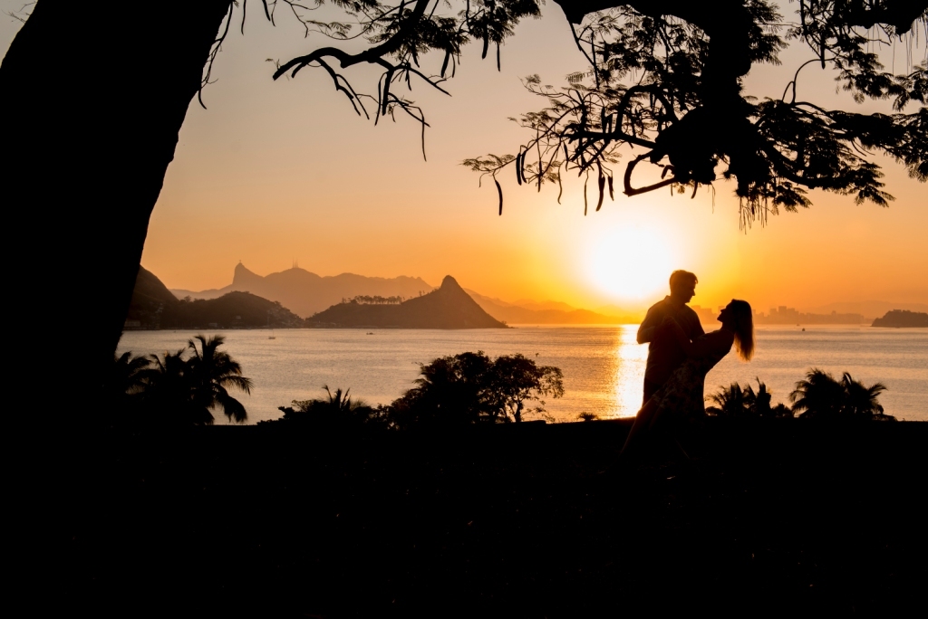 Pôr do Sol da Igrejinha de São Francisco em Niterói com casal em ensaio pré wedding para casamento ao ar livre feito pelo fotógrafo de casamentos famoso Gilson Freitas do Nossa Casa Estúdio com noivo e noiva felizes em dia romântico 