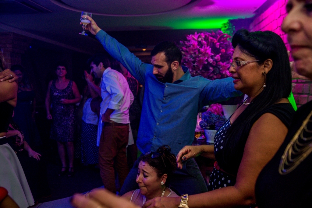 Nossa Casa Estúdio Gilson Freitas Fotógrafo profissional de casamentos fotografia de matrimônio em Niterói Rio de Janeiro com vestido branco e noivo casal na pista de dança e convidados dançando DJ Iluminação espaço Dimattoni felizes Noiva 