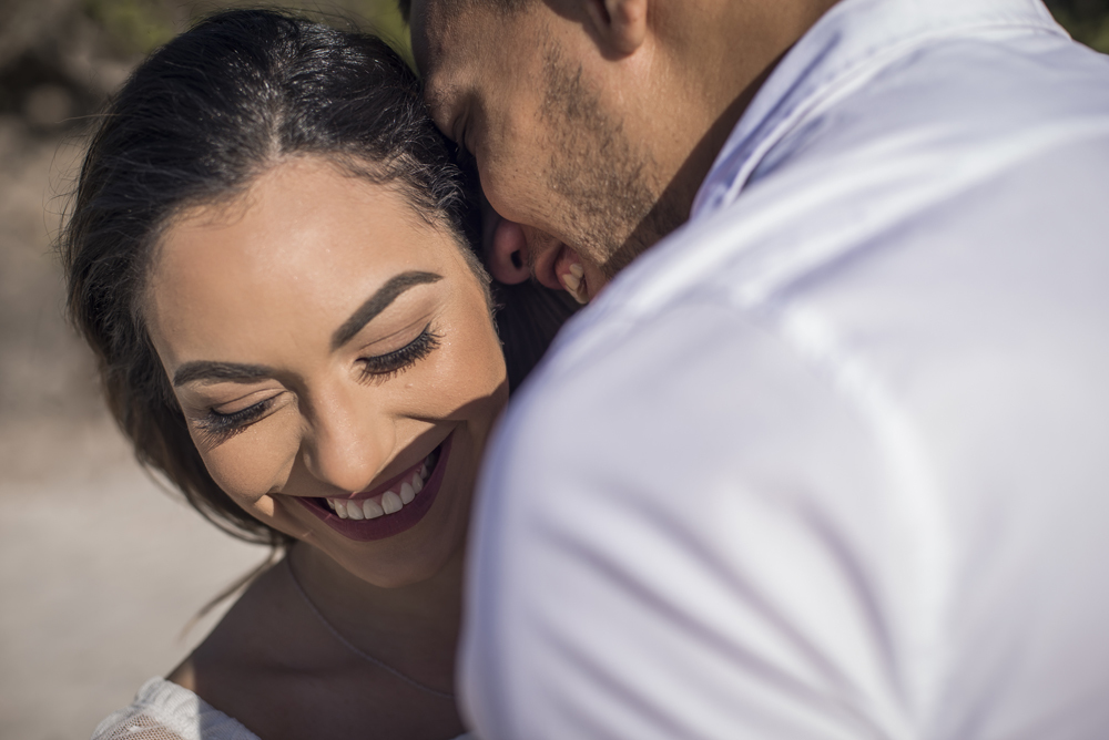 Melhor fotógrafo Nossa Casa Estúdio ensaio fotográfico profissional de casal na cidade de Niterói Rio de janeiro para pré wedding e casamento na praia de adão e eva ao por do sol na areia e mar com noivos/namorados vestidos de branco. Maquiagem noiva